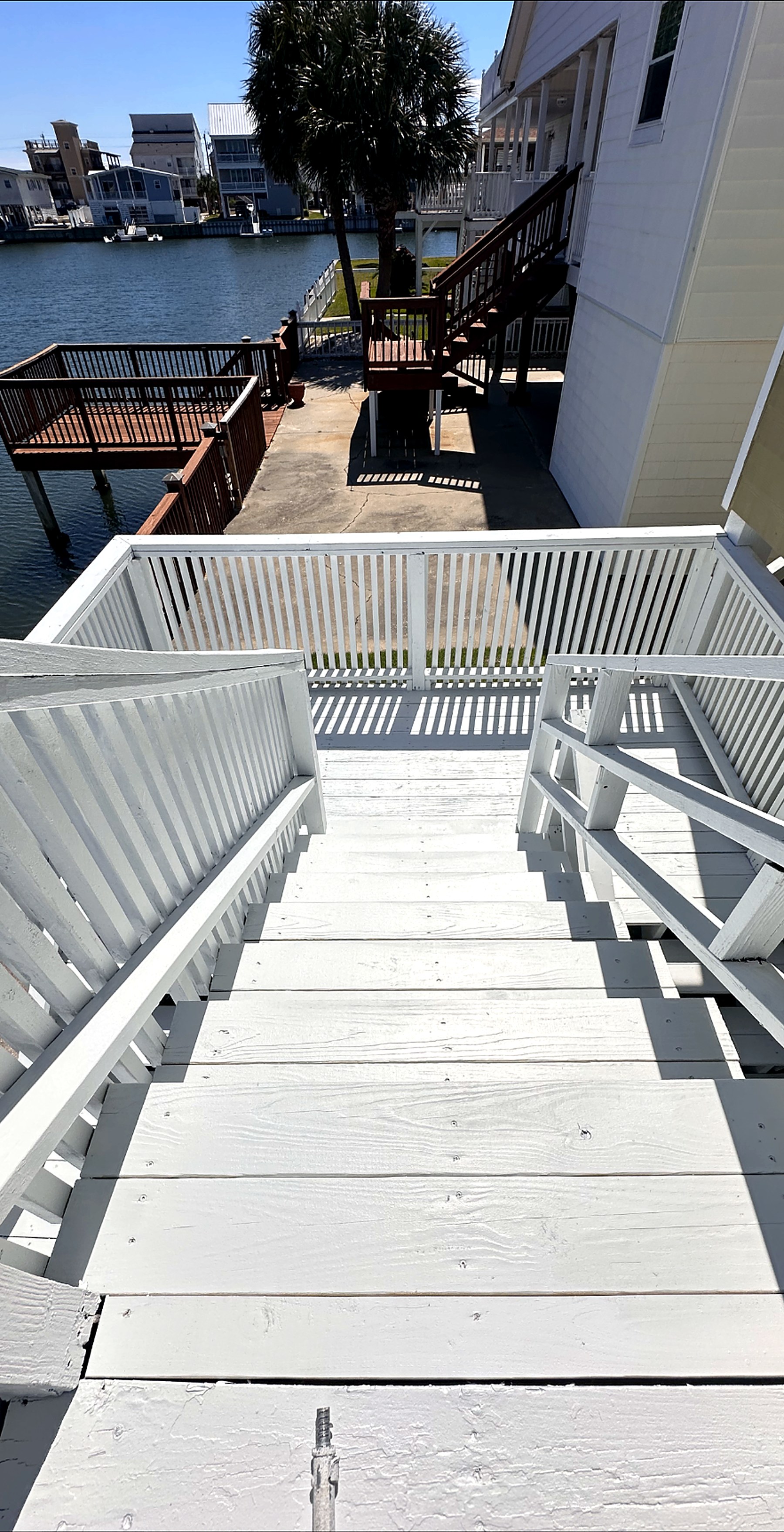 Waterfront deck stairs and railings coated in bright white deck paint overlooking a canal